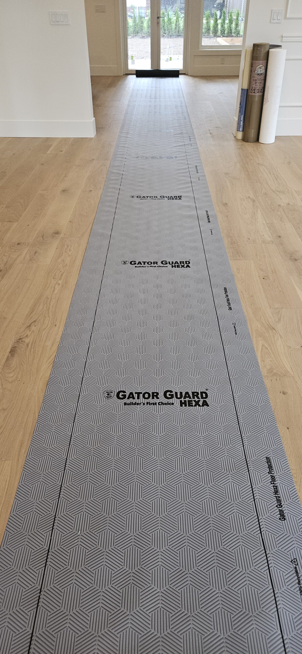 Close-up of Gator Guard® Gold heavy-duty floor protection roll standing upright on a white background — textured jobsite surface covering.