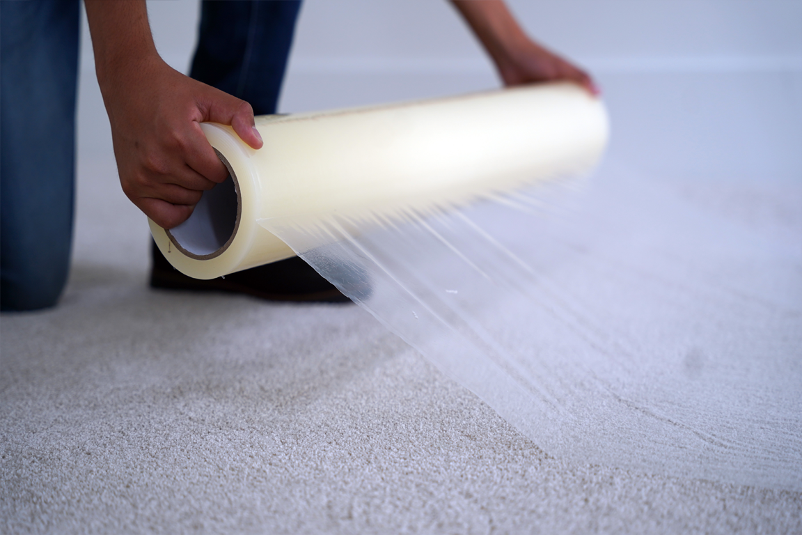Contractor applying Gator Guard Carpet Protection Film to safeguard floors during renovation. Heavy-duty temporary surface covering for carpeted construction sites.
